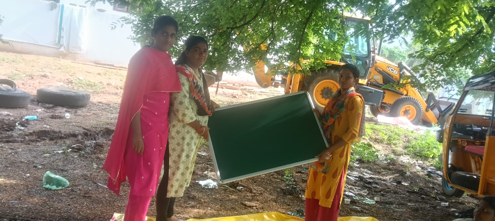 Volunteer teachers receiving a blackboard delivered by The Jayavel Impex at a village tuition centre near Dindigul